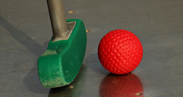 Ein Grüner Minigolfschläger vor einem roten Golfball